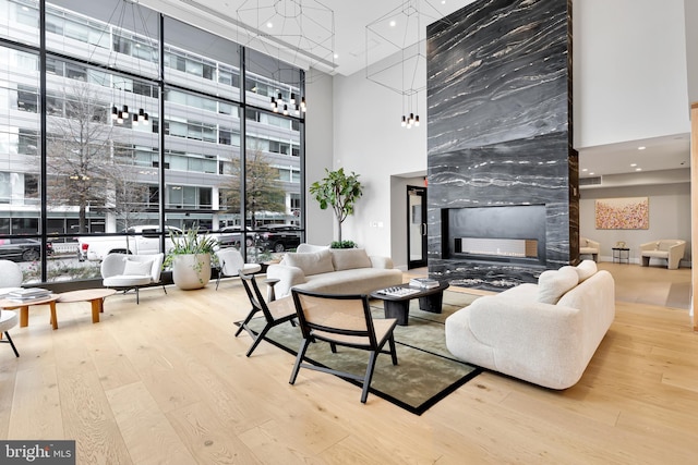 living room with a high ceiling, a high end fireplace, a wealth of natural light, and wood-type flooring