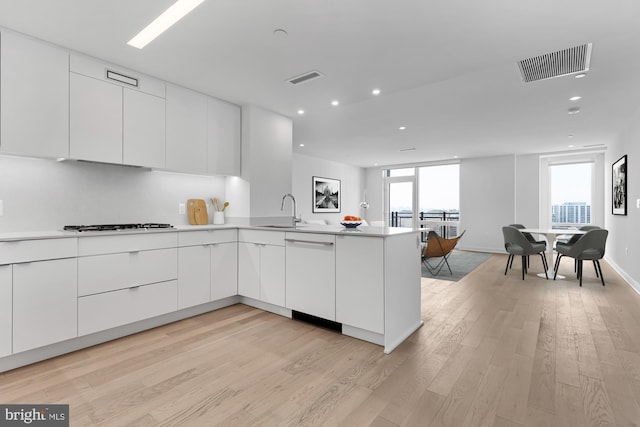 kitchen featuring white appliances, a wealth of natural light, sink, kitchen peninsula, and white cabinets