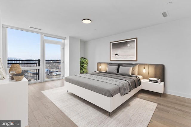 bedroom featuring access to exterior, expansive windows, and wood-type flooring