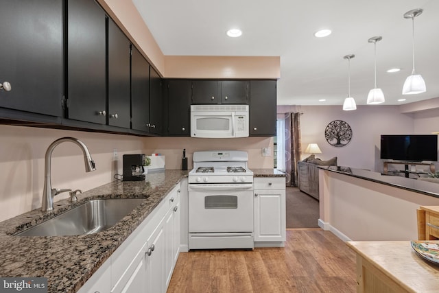 kitchen featuring light wood-style flooring, open floor plan, a sink, white appliances, and dark cabinetry