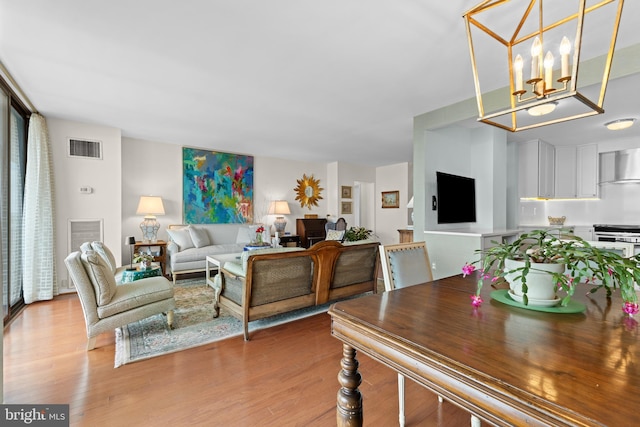 living room featuring a chandelier, light wood-type flooring, and visible vents