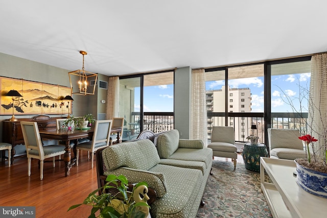 living area featuring a notable chandelier, wood finished floors, and floor to ceiling windows