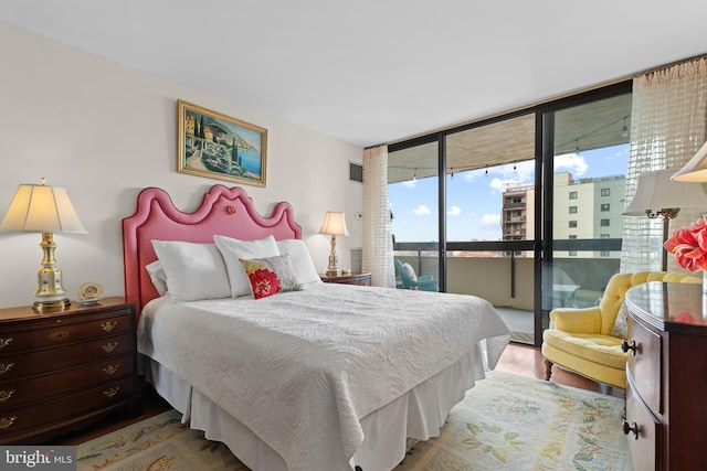 bedroom featuring access to exterior, floor to ceiling windows, and wood finished floors