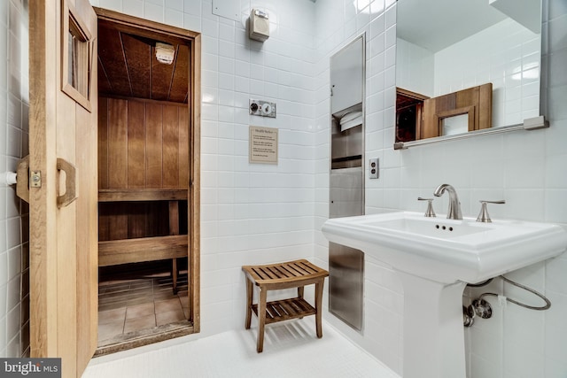 bathroom with a sink, a sauna, backsplash, and tile walls