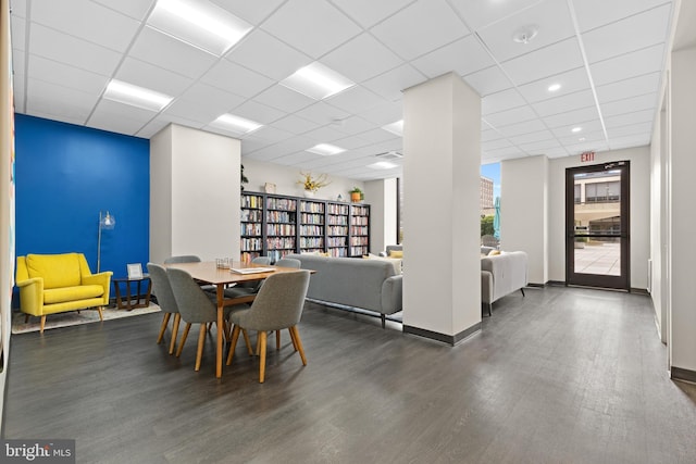 dining area featuring a drop ceiling, dark wood finished floors, and baseboards