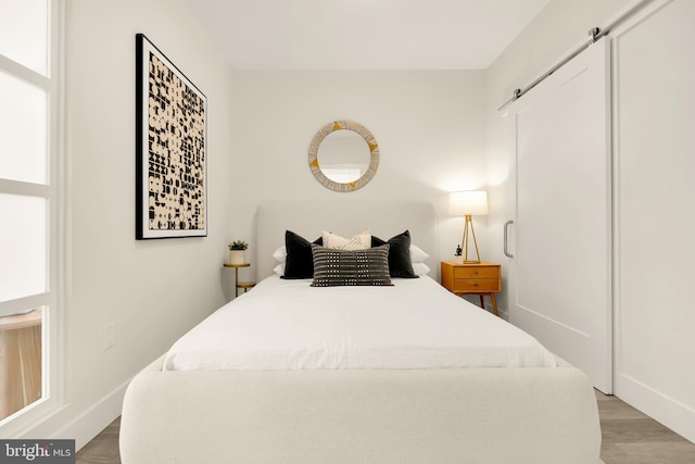 bedroom featuring a barn door and light hardwood / wood-style flooring