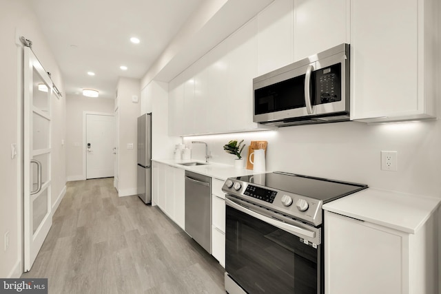 kitchen featuring sink, white cabinets, stainless steel appliances, and light hardwood / wood-style floors