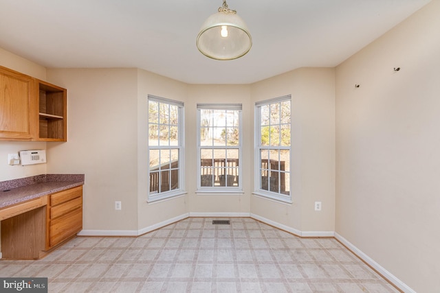 unfurnished dining area featuring baseboards, visible vents, and built in study area