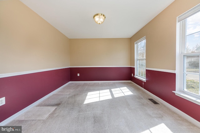 empty room featuring baseboards, carpet floors, and visible vents
