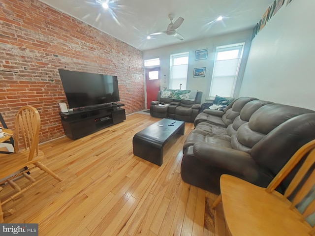 living area with brick wall, wood-type flooring, and ceiling fan