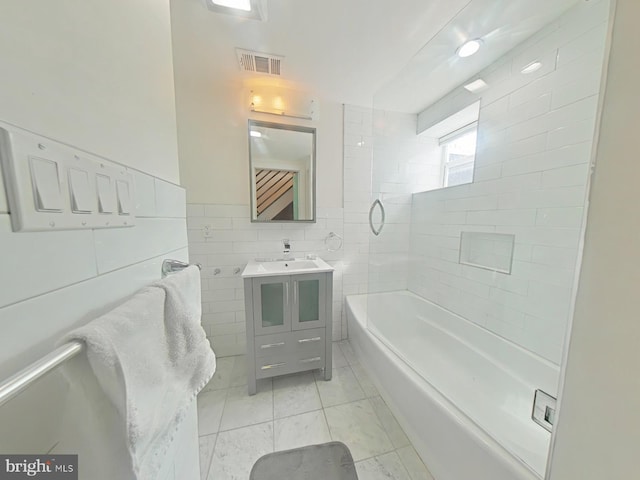 bathroom with visible vents, shower / bathtub combination, vanity, and tile walls