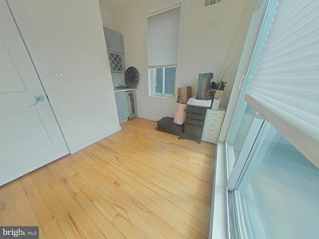 interior space with a dry bar, light wood-style flooring, and visible vents