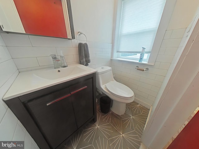 half bathroom featuring toilet, vanity, and tile walls