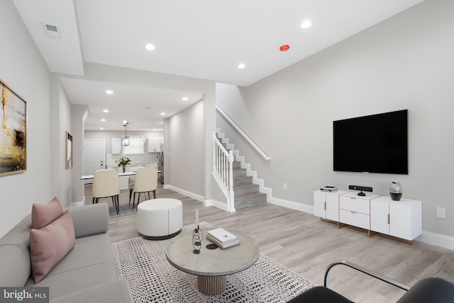 living area featuring recessed lighting, visible vents, baseboards, stairs, and light wood finished floors