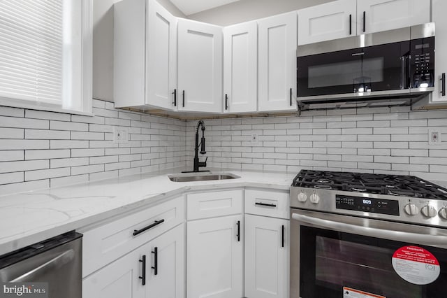 kitchen with white cabinets, tasteful backsplash, stainless steel appliances, and a sink