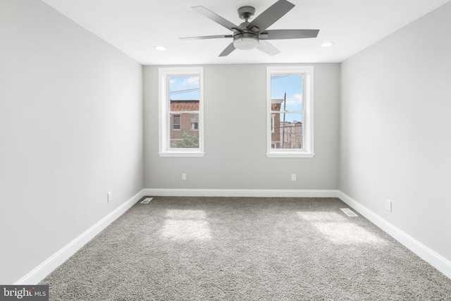 empty room featuring carpet flooring, a healthy amount of sunlight, visible vents, and baseboards