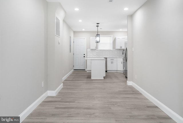 kitchen with baseboards, white cabinets, light countertops, tasteful backsplash, and pendant lighting