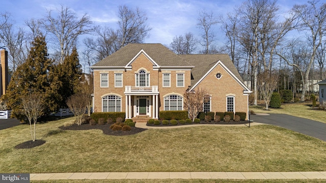 colonial-style house with brick siding, a front yard, and aphalt driveway