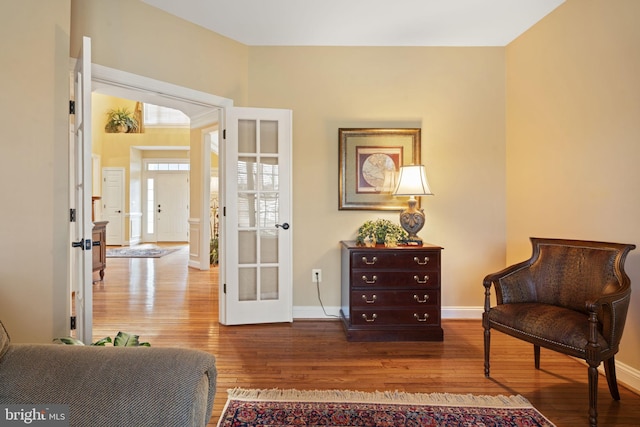 sitting room featuring french doors, baseboards, and wood finished floors