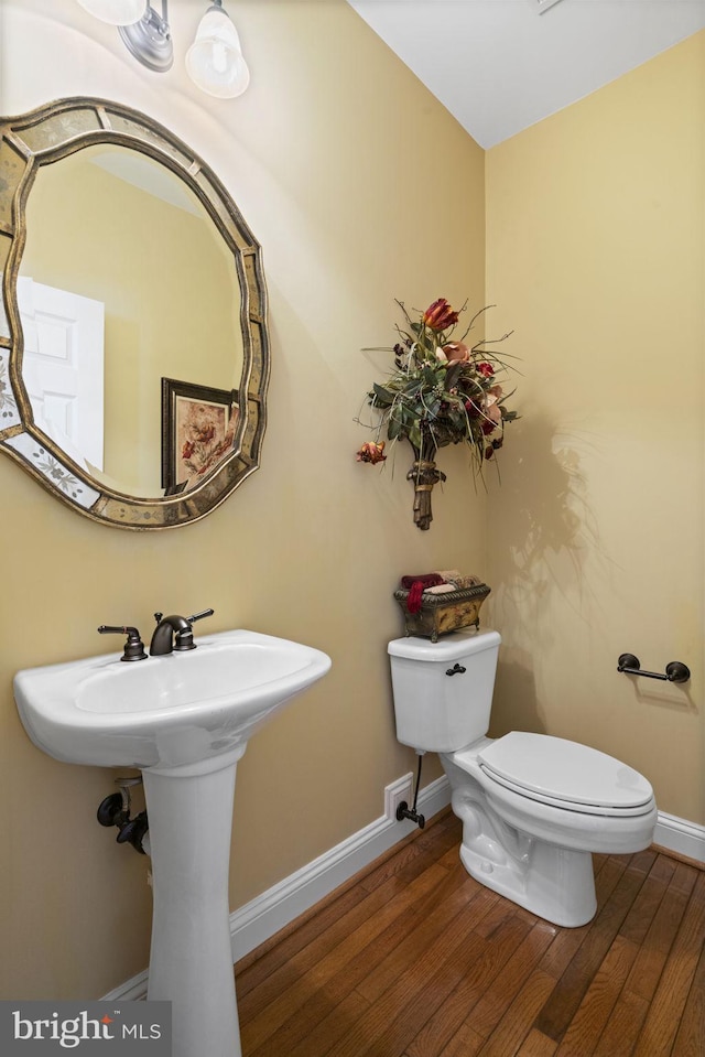 bathroom with wood finished floors, toilet, and baseboards