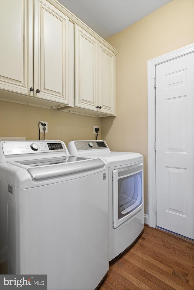 washroom with cabinet space, dark wood-style flooring, and washing machine and clothes dryer