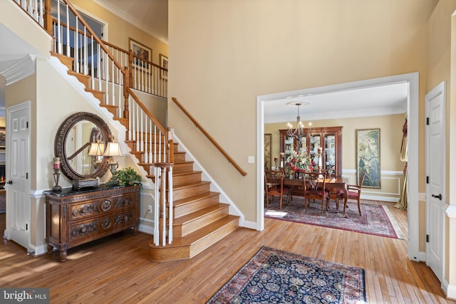 foyer with stairs, a high ceiling, crown molding, and wood finished floors