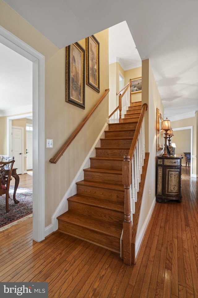 stairs featuring baseboards, wood finished floors, and ornamental molding