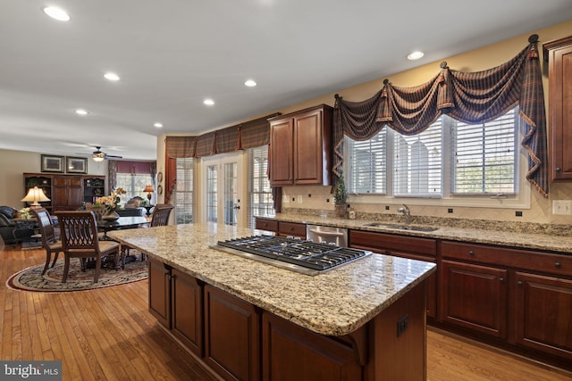 kitchen featuring open floor plan, a center island, stainless steel appliances, light wood-type flooring, and a sink