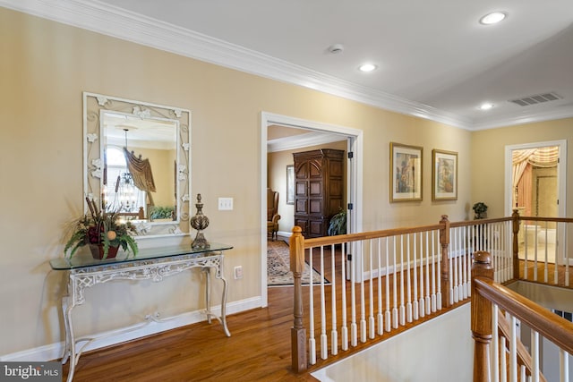 corridor with recessed lighting, wood finished floors, an upstairs landing, visible vents, and crown molding