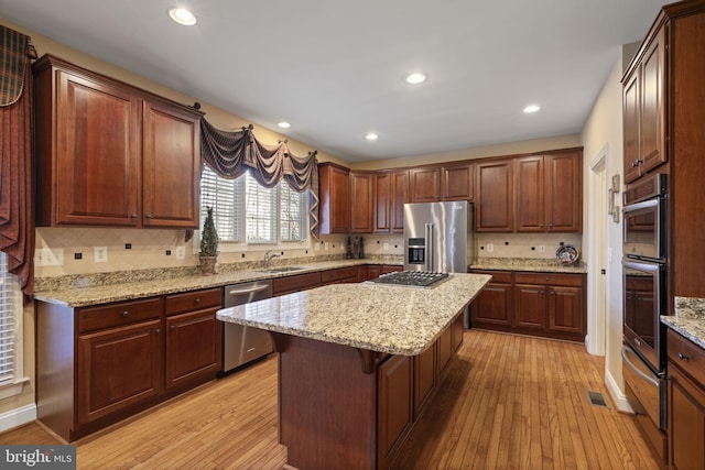 kitchen featuring a kitchen breakfast bar, appliances with stainless steel finishes, light wood-type flooring, and a center island