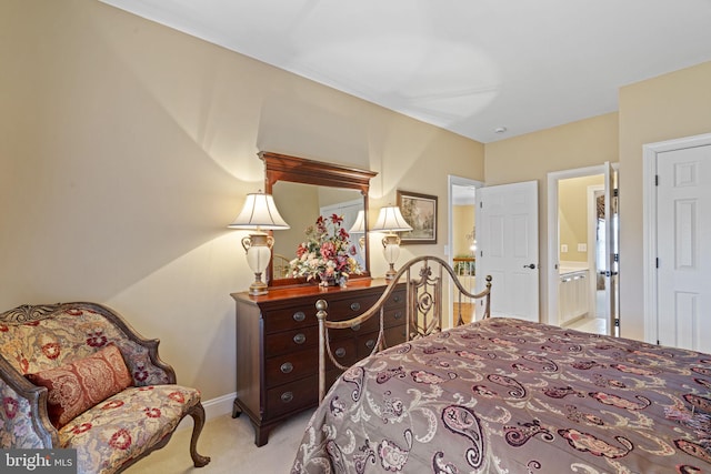 bedroom featuring baseboards, ensuite bathroom, and light colored carpet