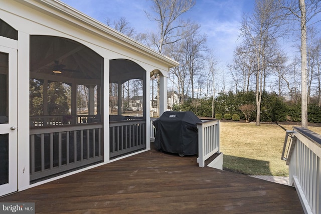 wooden terrace with a sunroom, a grill, a ceiling fan, and a yard