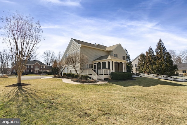 view of side of home featuring a sunroom, a lawn, and fence