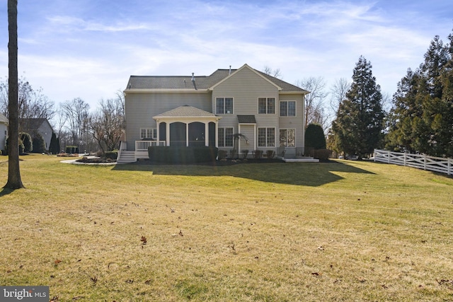 rear view of property with a gazebo, a lawn, and fence