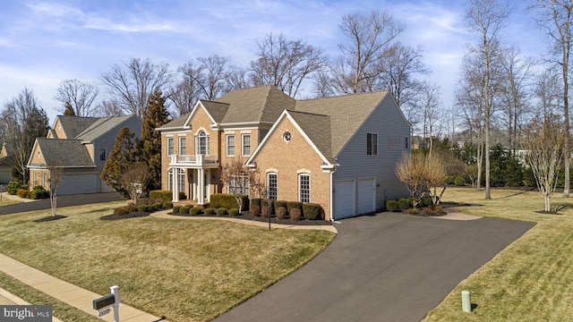 view of front facade with a balcony, driveway, a front yard, and brick siding