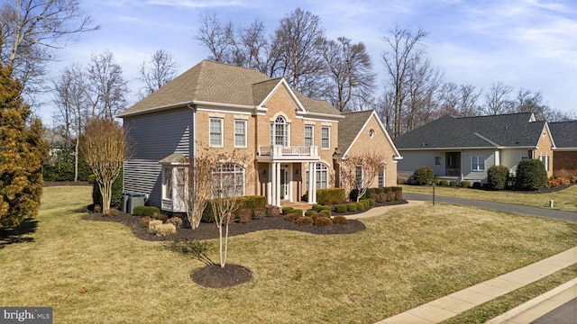 view of front facade with a balcony, roof with shingles, central air condition unit, a front lawn, and brick siding