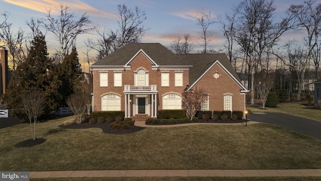 colonial home featuring a yard and brick siding