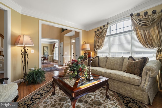 living area with baseboards, ornamental molding, and wood finished floors