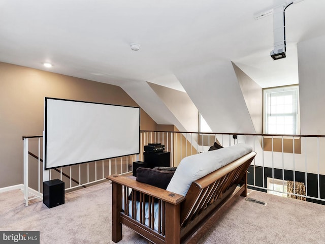 carpeted home theater featuring lofted ceiling and visible vents