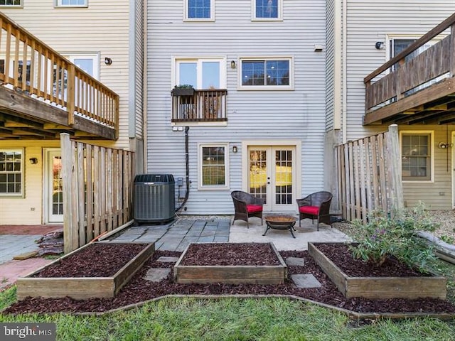 back of property featuring a vegetable garden, french doors, a fire pit, central air condition unit, and a patio area