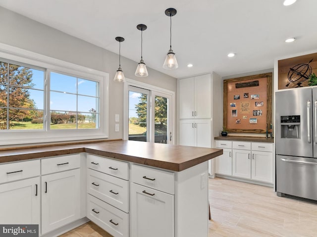 kitchen featuring a peninsula, stainless steel fridge with ice dispenser, recessed lighting, hanging light fixtures, and white cabinetry