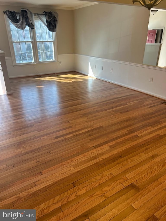 empty room featuring wood finished floors and ornamental molding