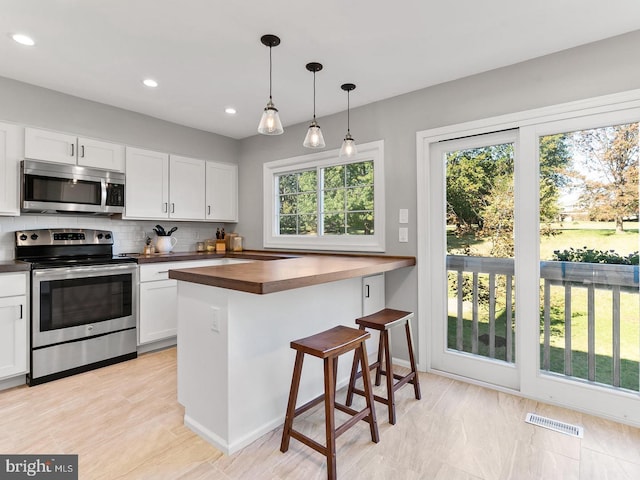 kitchen with visible vents, backsplash, white cabinetry, and stainless steel appliances