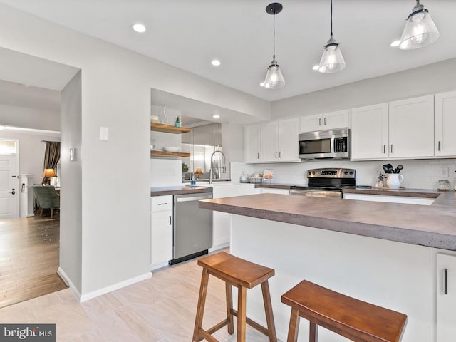 kitchen featuring pendant lighting, a breakfast bar, tasteful backsplash, white cabinetry, and stainless steel appliances