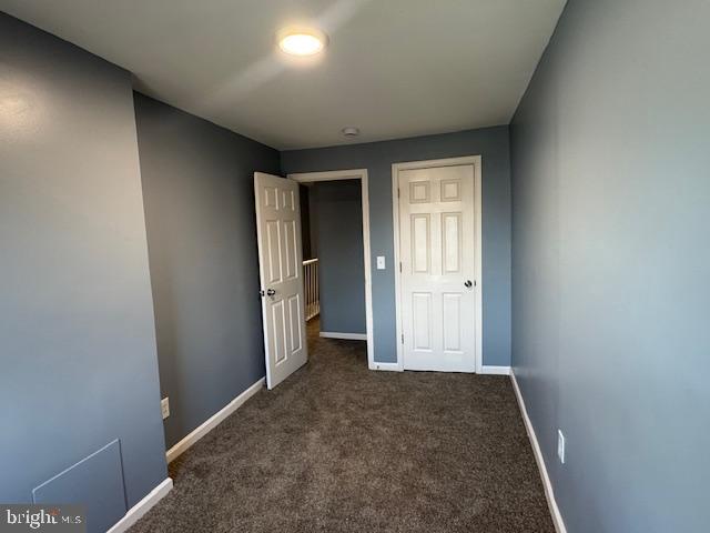 unfurnished bedroom with dark carpet