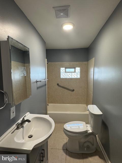 full bathroom with tiled shower / bath, tile patterned flooring, vanity, and toilet