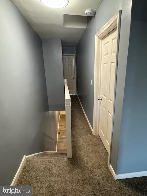 corridor featuring dark colored carpet