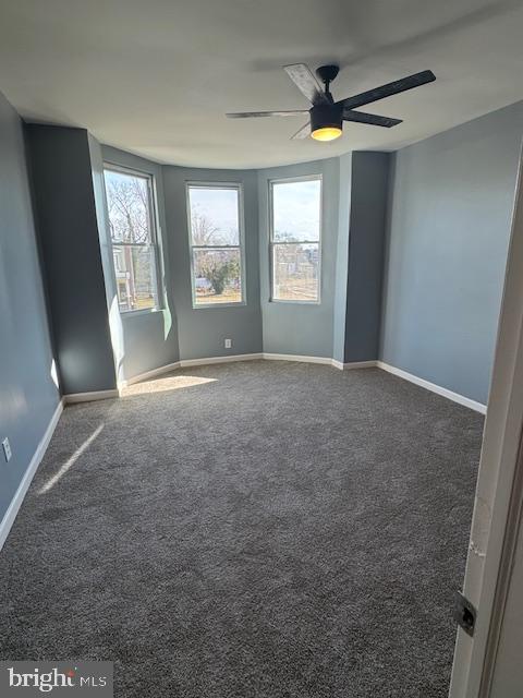 carpeted empty room with ceiling fan and plenty of natural light