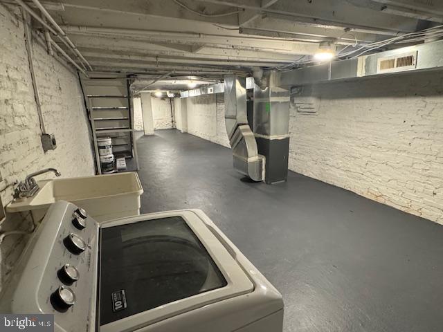 basement featuring heating unit and washer / dryer