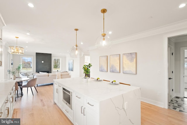 kitchen with pendant lighting, light stone counters, white cabinetry, and a center island